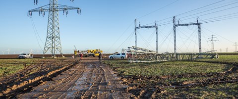Monteure mit Kran auf einem Feld beim Netzausbau Monteure mit Kran auf einem Feld beim Netzausbau