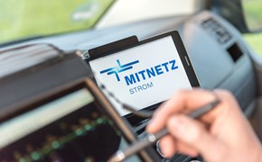 Portables Eingabegerät und Smartphone, auf dem das MITNETZ STROM-Logo zu sehen ist, im Innern eines Fahrzeugs Portables Eingabegerät und Smartphone, auf dem das MITNETZ STROM-Logo zu sehen ist, im Innern eines Fahrzeugs