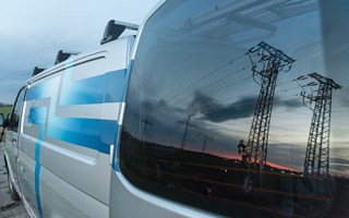 Hochspannungsmasten vor einer Abendstimmung spiegeln sich im Fenster eines Technikfahrzeugs Hochspannungsmasten vor einer Abendstimmung spiegeln sich im Fenster eines Technikfahrzeugs