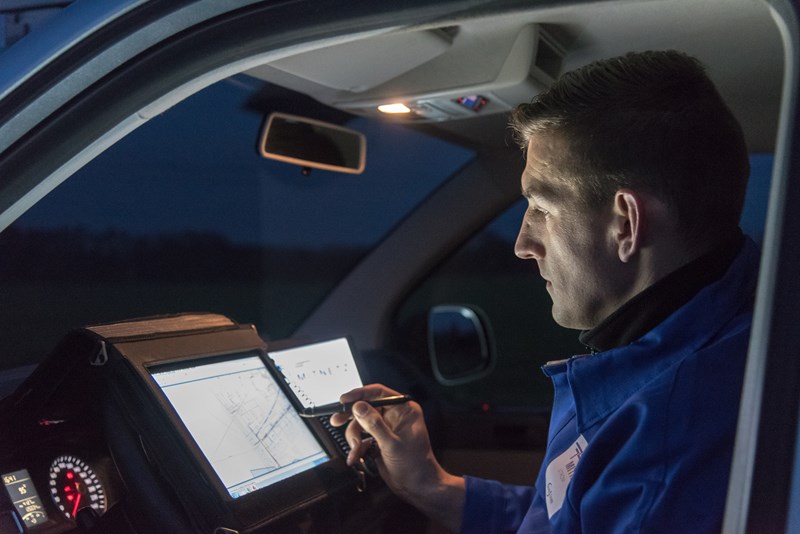 Im erleuchteten Cockpit eines Fahrzeugs arbeitet ein Techniker nachts an einem portablen Eingabegerät
