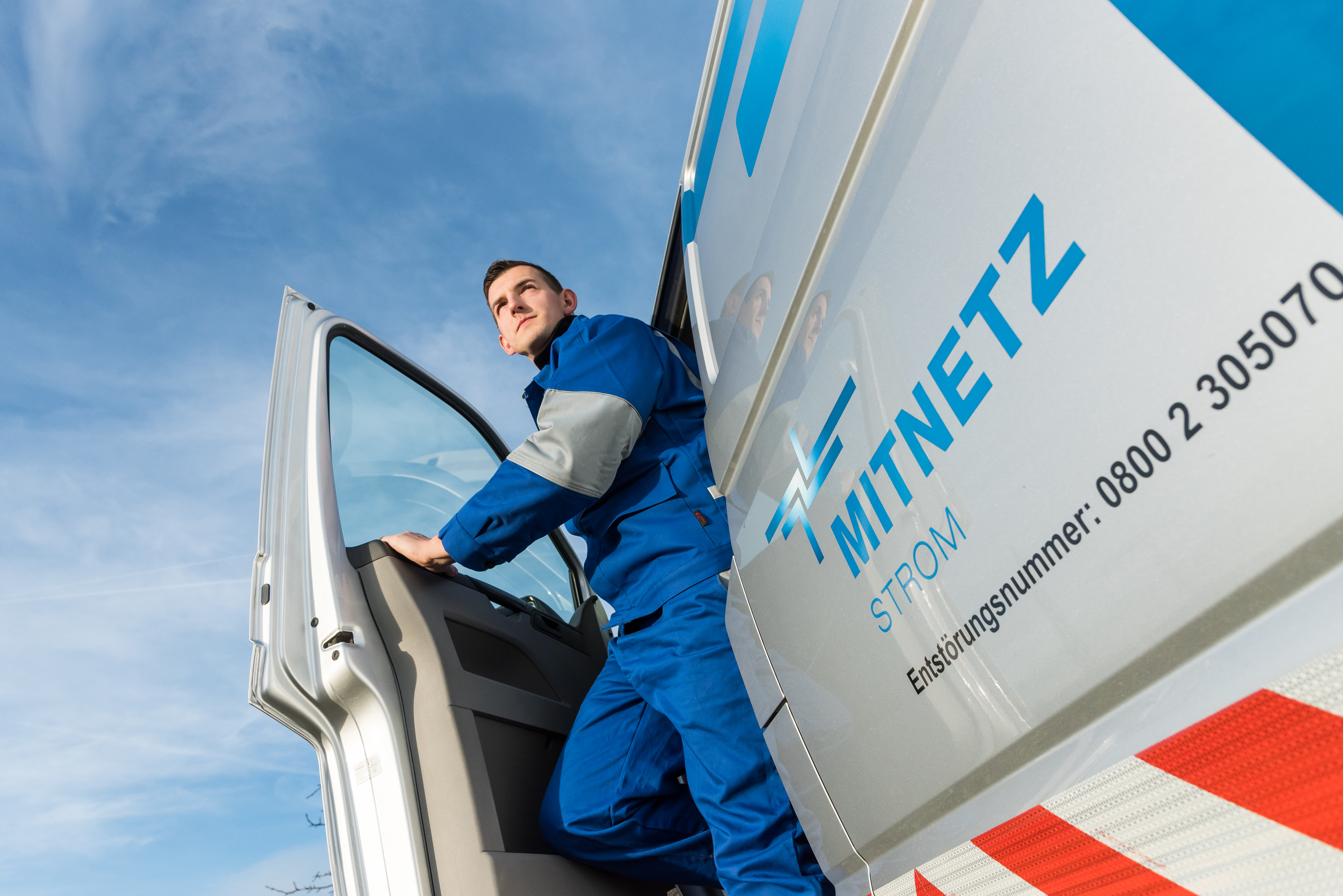 Ein Techniker steigt vor blauem Himmel aus einem Technikfahrzeug