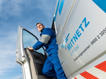 Ein Techniker steigt vor blauem Himmel aus einem Technikfahrzeug Ein Techniker steigt vor blauem Himmel aus einem Technikfahrzeug