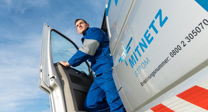 Ein Techniker steigt vor blauem Himmel aus einem Technikfahrzeug Ein Techniker steigt vor blauem Himmel aus einem Technikfahrzeug