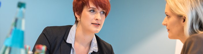 Zwei Frauen im Gespräch an einem Tisch, auf dem Getränke und Tassen stehen Zwei Frauen im Gespräch an einem Tisch, auf dem Getränke und Tassen stehen