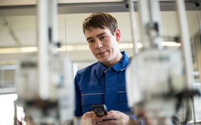 Techniker mit kleinem Messgerät in beiden Händen blickt konzentriert auf Geräte Techniker mit kleinem Messgerät in beiden Händen blickt konzentriert auf Geräte