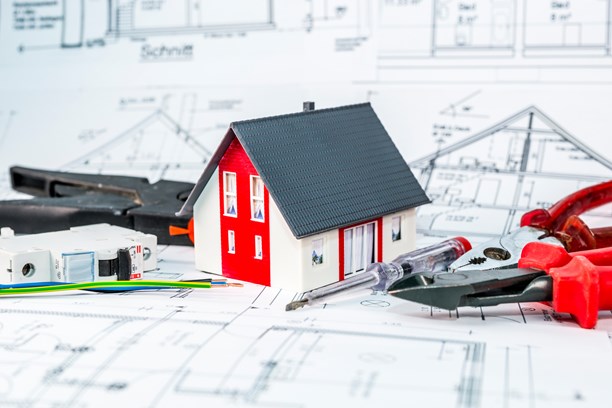 Kleines Hausmodell und Werkzeug auf einem Bauplan Kleines Hausmodell und Werkzeug auf einem Bauplan