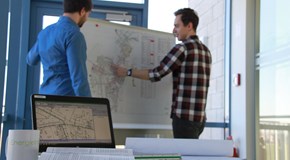 Zwei Personen stehen vor einer Pinnwand und sprechen über eine Zielnetzplanung 2 Personen stehen vor einer Pinnwand und sprechen über eine Zielnetzplanung