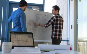 Zwei Personen stehen vor einer Pinnwand und sprechen über eine Zielnetzplanung 2 Personen stehen vor einer Pinnwand und sprechen über eine Zielnetzplanung