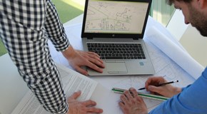 Mitarbeiter bearbeiten Netzplan und vergleichen Daten im Laptop Mitarbeiter bearbeiten Netzplan und vergleichen Daten im Laptop