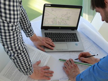 Mitarbeiter bearbeiten Netzplan und vergleichen Daten im Laptop Mitarbeiter bearbeiten Netzplan und vergleichen Daten im Laptop