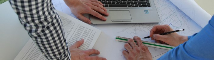 Mitarbeiter bearbeiten Netzplan und vergleichen Daten im Laptop Mitarbeiter bearbeiten Netzplan und vergleichen Daten im Laptop