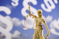 Justitia-Statue vor einem blauen Hintergrund mit weißen Paragrafenzeichen - Bildmontage Justitia-Statue vor einem blauen Hintergrund mit weißen Paragrafenzeichen - Bildmontage