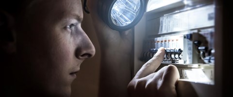 Mann mit Taschenlampe am Stromkasten Mann mit Taschenlampe am Stromkasten