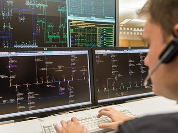 Mitarbeiter mit einem Headset vor mehreren Monitoren Mitarbeiter mit einem Headset vor mehreren Monitoren