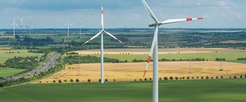 Windräder in einer Landschaft mit Feldern und Straßen Windräder in einer Landschaft mit Feldern und Straßen
