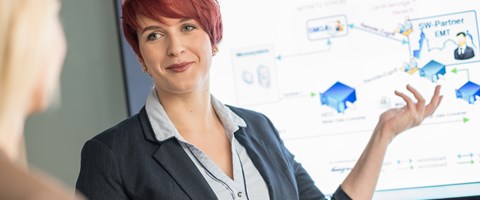 Zwei Frauen im Gespräch bei einer Präsentation, eine Frau trägt kurze rote Haare Zwei Frauen im Gespräch bei einer Präsentation, eine Frau trägt kurze rote Haare