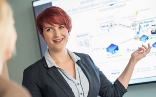Eine Frau deutet im Gespräch bei einer Präsentation auf eine Grafik Eine Frau deutet im Gespräch bei einer Präsentation auf eine Grafik