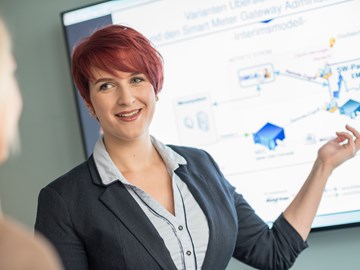 Eine Frau deutet im Gespräch bei einer Präsentation auf eine Grafik Eine Frau deutet im Gespräch bei einer Präsentation auf eine Grafik