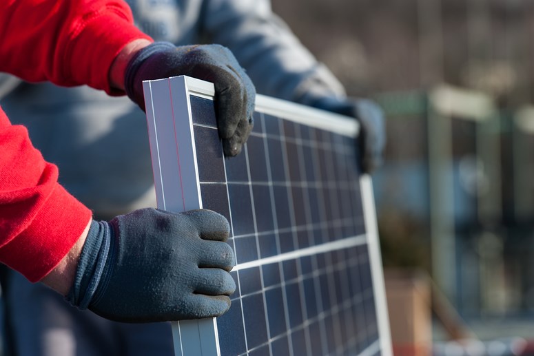 Rote Ärmel und behandschuhte Hände bei der Montage einer PV-Anlage Rote Ärmel und behandschuhte Hände bei der Montage einer PV-Anlage
