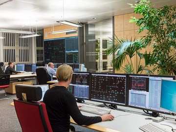 Drei Mitarbeiter sitzen im Büro der Schaltleitung vor Monitoren Drei Mitarbeiter sitzen im Büro der Schaltleitung vor Monitoren