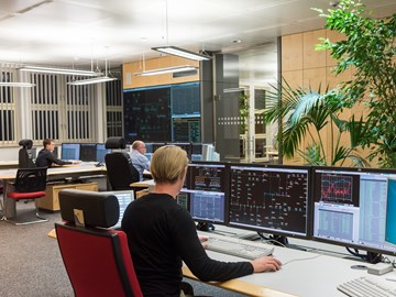 Drei Mitarbeiter sitzen im Büro der Schaltleitung vor Monitoren Drei Mitarbeiter sitzen im Büro der Schaltleitung vor Monitoren