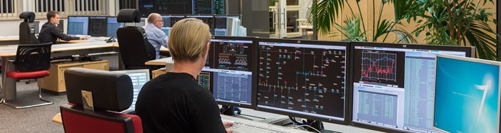 Drei Mitarbeiter sitzen im Büro der Schaltleitung vor Monitoren Drei Mitarbeiter sitzen im Büro der Schaltleitung vor Monitoren