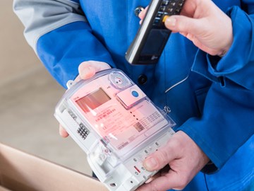 Hände mit Geräten bei der Ablesung eines Stromzählers Hände mit Geräten bei der Ablesung eines Stromzählers