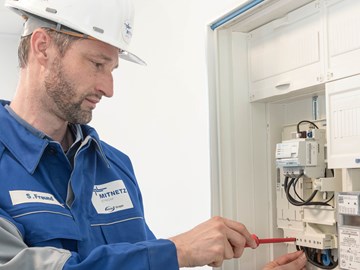 Mitarbeiter mit rotem Schraubenzieher arbeitet an einem Stromzähler Mitarbeiter mit rotem Schraubenzieher arbeitet an einem Stromzähler