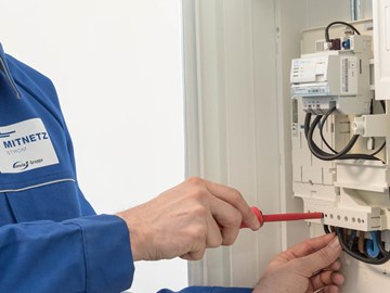 Mitarbeiter mit rotem Schraubenzieher arbeitet an einem Stromzähler Mitarbeiter mit rotem Schraubenzieher arbeitet an einem Stromzähler