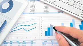 Hand mit Kugelschreiber über Diagrammen neben einer Tastatur - Nahaufnahme Hand mit Kugelschreiber über Diagrammen neben einer Tastatur - Nahaufnahme