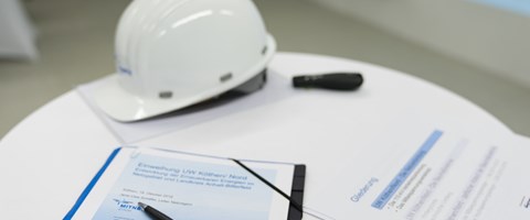 Auf einem Tisch liegen Unterlagen mit einem Kugelschreiber und ein weißer Helm Auf einem Tisch liegen Unterlagen mit einem Kugelschreiber und ein weißer Helm