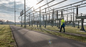 Mitarbeiter mit Helm und Warnschutzjacke bei Anlagen im Umspannwerk unter freiem Himmel Mitarbeiter mit Helm und Warnschutzjacke bei Anlagen im Umspannwerk unter freiem Himmel