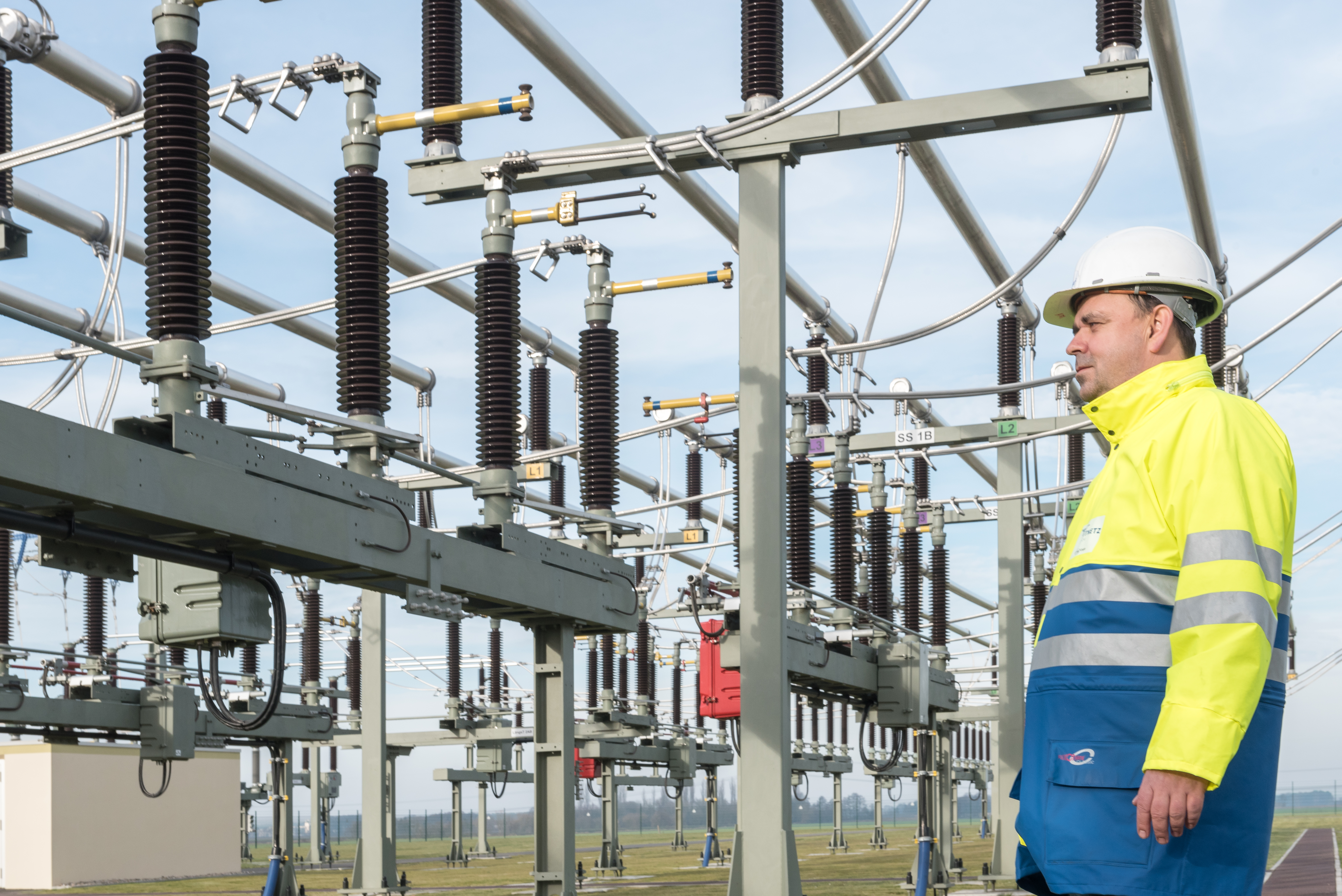 Mitarbeiter mit Helm und Warnschutzjacke an einer Anlage
