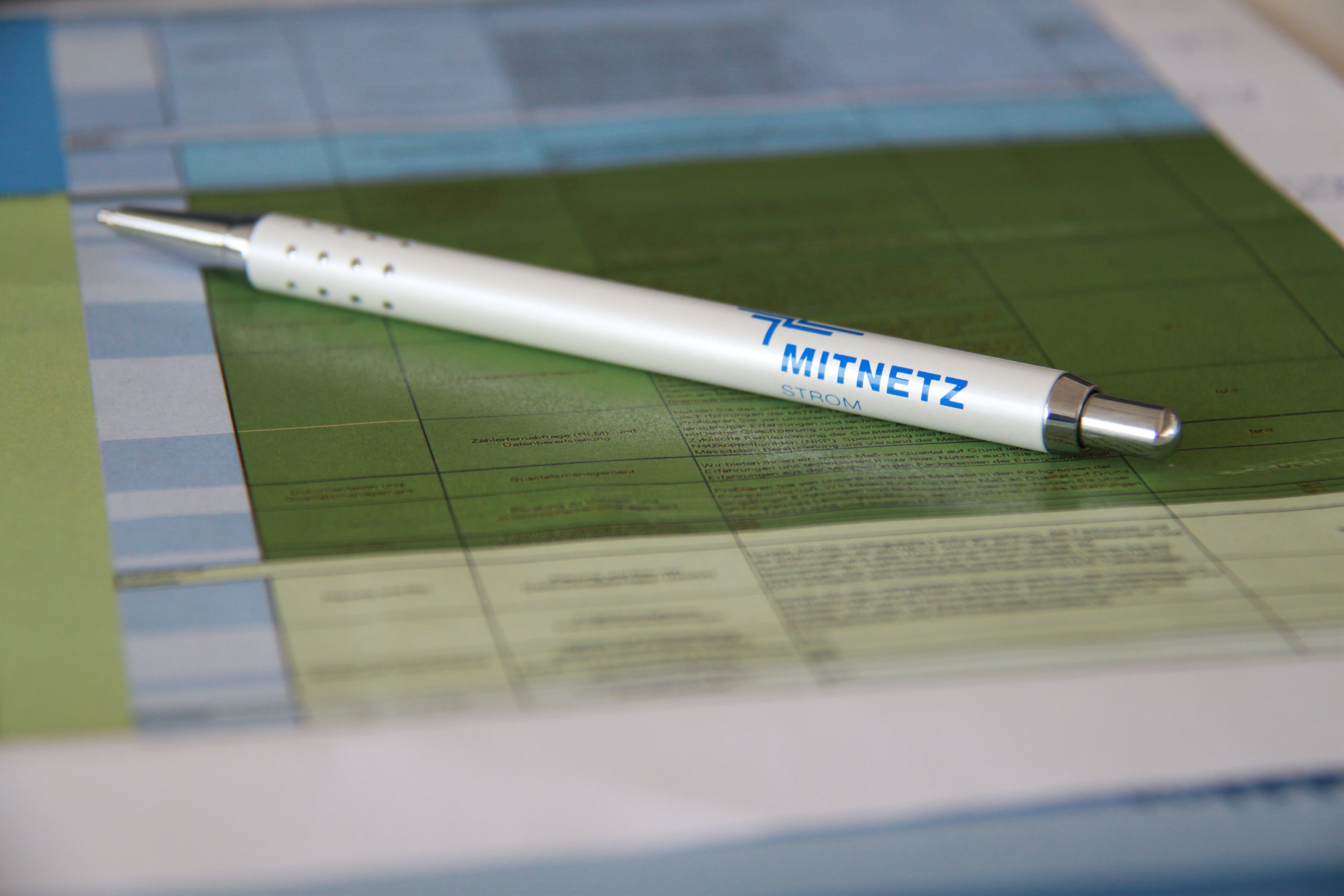 Kugelschreiber mit MITNETZ STROM-Logo auf Unterlagen - Nahaufnahme