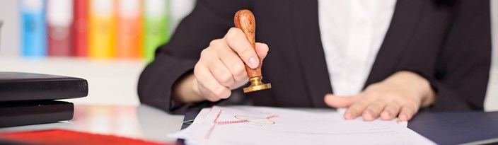 Hände einer Frau mit Siegelstempel über einer Urkunde Hände einer Frau mit Siegelstempel über einer Urkunde