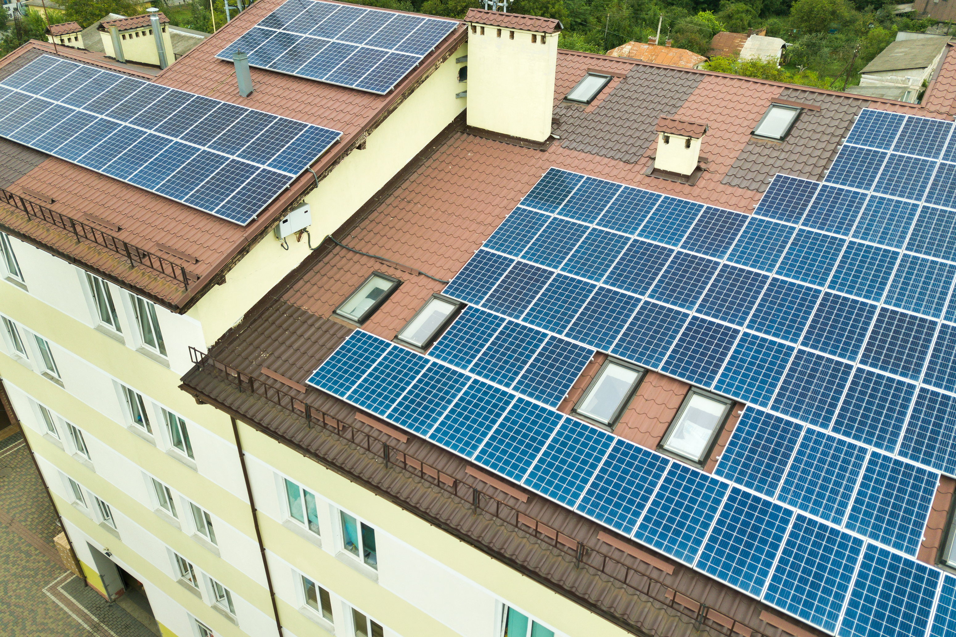 Luftaufnahme von Solarkraftwerk mit blauen Photovoltaik-Paneele n. Rand des Daches des Mehrfamilienhauses
