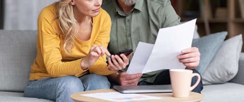 Verheiratetes Paar mittleren Alters plant gemeinsam Budget, liest Papiere und berechnet Ausgaben Verheiratetes Paar mittleren Alters plant gemeinsam Budget, liest Papiere und berechnet Ausgaben