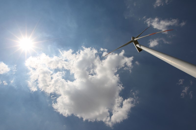 Windrad aus Froschperspektive mit Sonne und Wolken