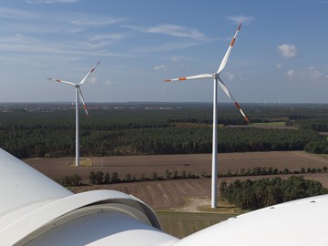 Sicht von dem Kopf eines Windrads auf ein Feld mit zwei weiteren Windrädern Sicht von dem Kopf eines Windrads auf ein Feld mit zwei weiteren Windrädern