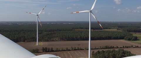 Sicht von dem Kopf eines Windrads auf ein Feld mit zwei weiteren Windrädern Sicht von dem Kopf eines Windrads auf ein Feld mit zwei weiteren Windrädern