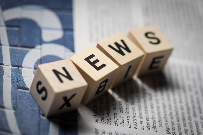 Vier Holzwürfel auf einer Zeitung bilden das Wort „News Vier Holzwürfel auf einer Zeitung bilden das Wort „News