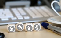 Vier Holzwürfel auf einem Schreibtisch neben einem Kugelschreiber vor einer Tastatur zeigen alle das Paragrafenzeichen Vier Holzwürfel auf einem Schreibtisch neben einem Kugelschreiber vor einer Tastatur zeigen alle das Paragrafenzeichen